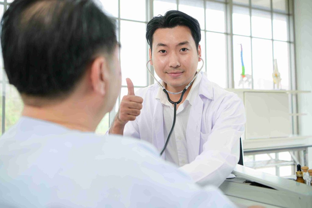 Doctor examining a patient and giving the thumbs up sign.