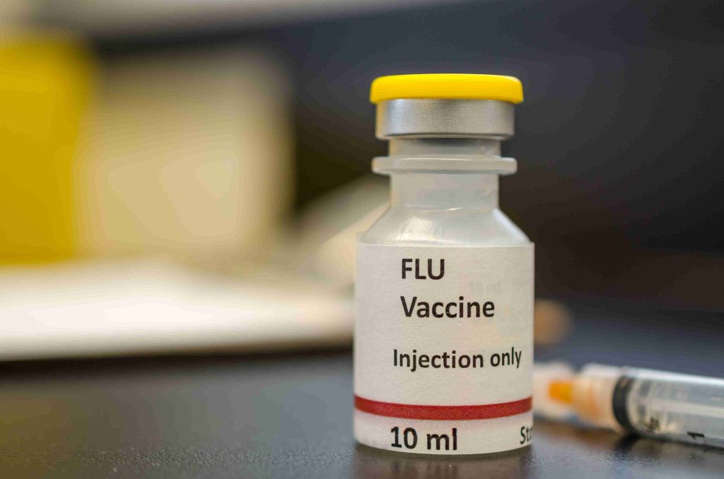 Image of a flu vaccine vial with an injection next to it.